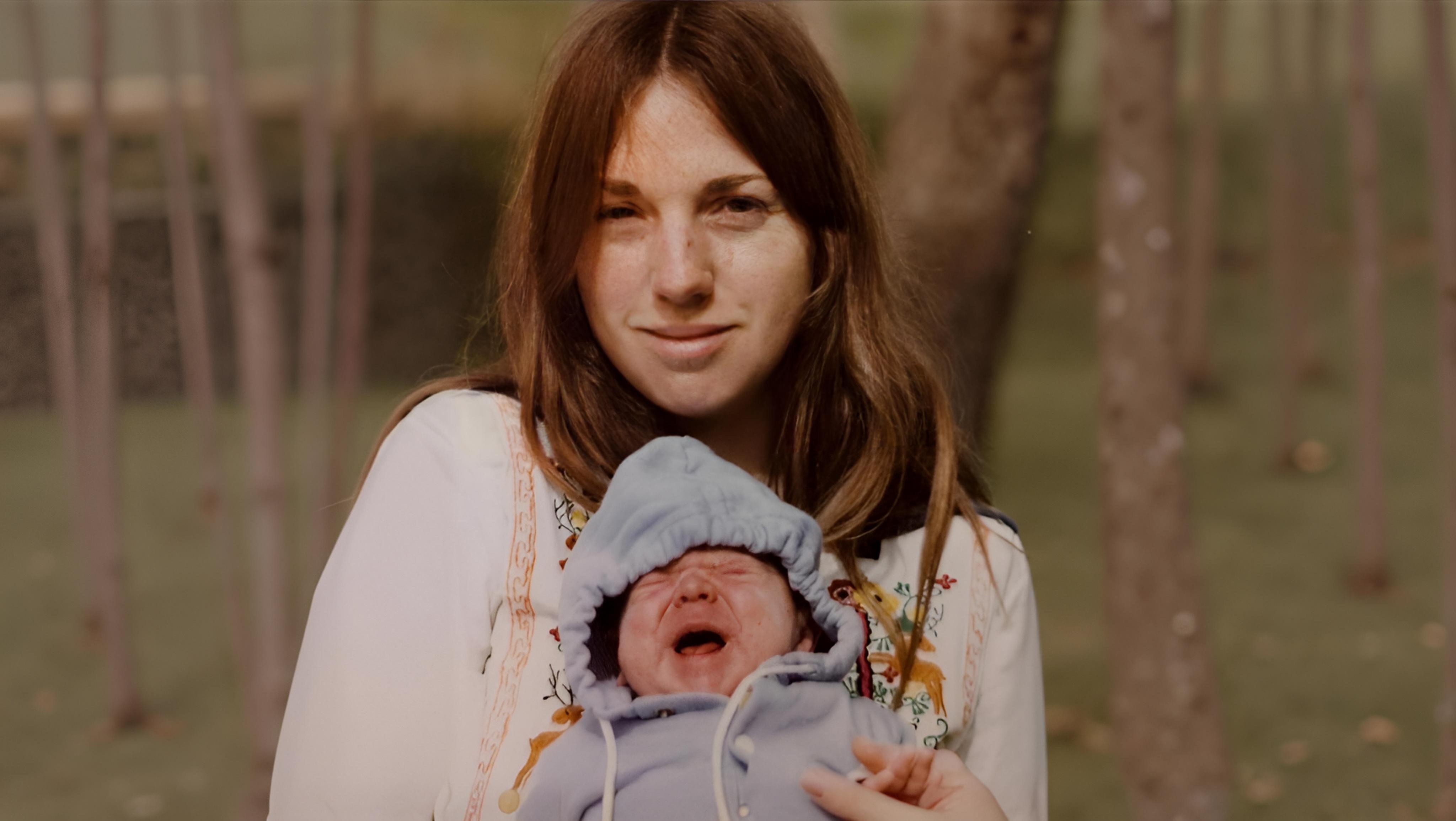 A mother holding a crying baby after the baby exceeds their daily people quota