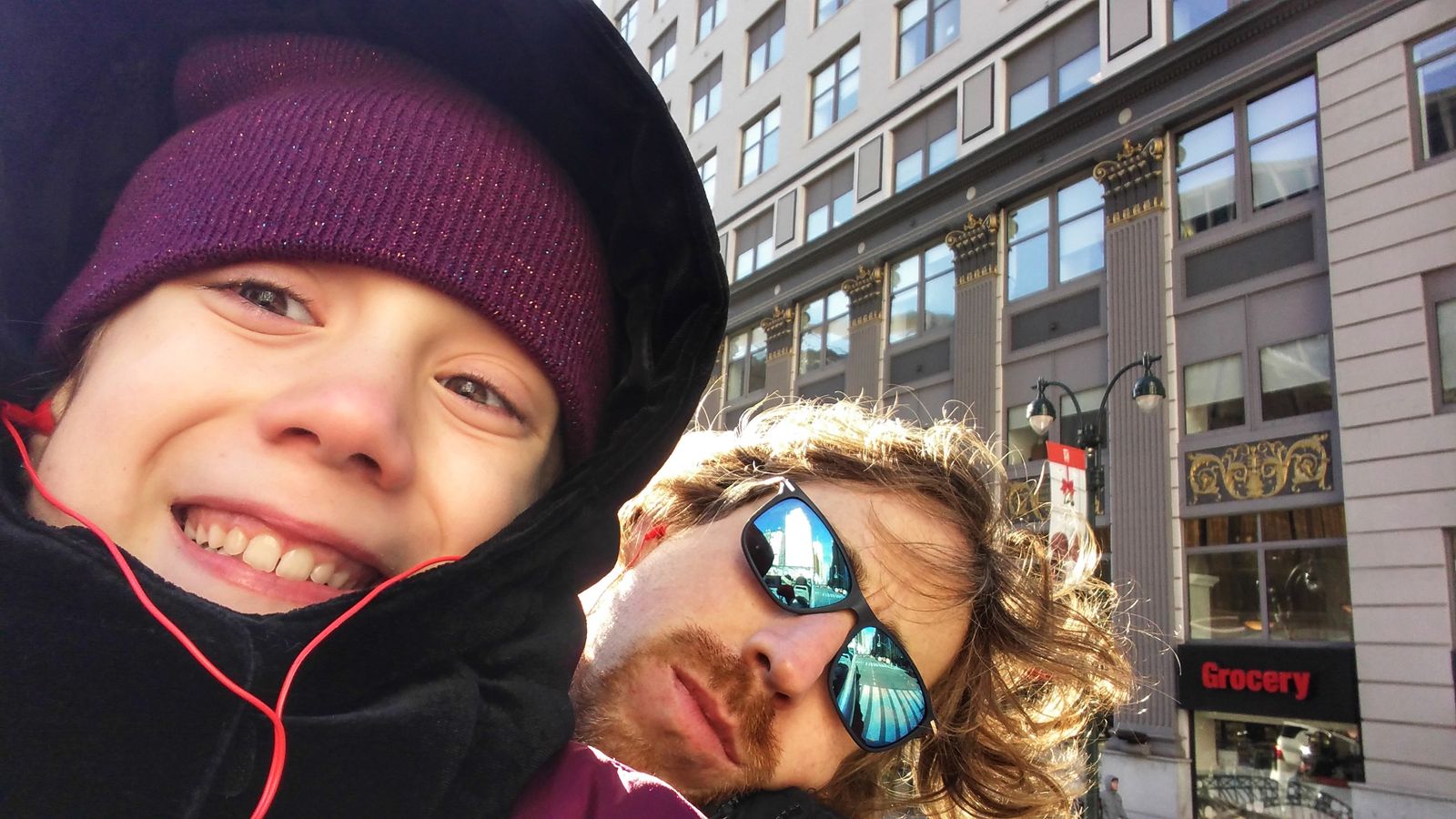 Father and daughter bundled up on a cold city morning — she’s radiant, he’s windblown, both surviving New York and each other.